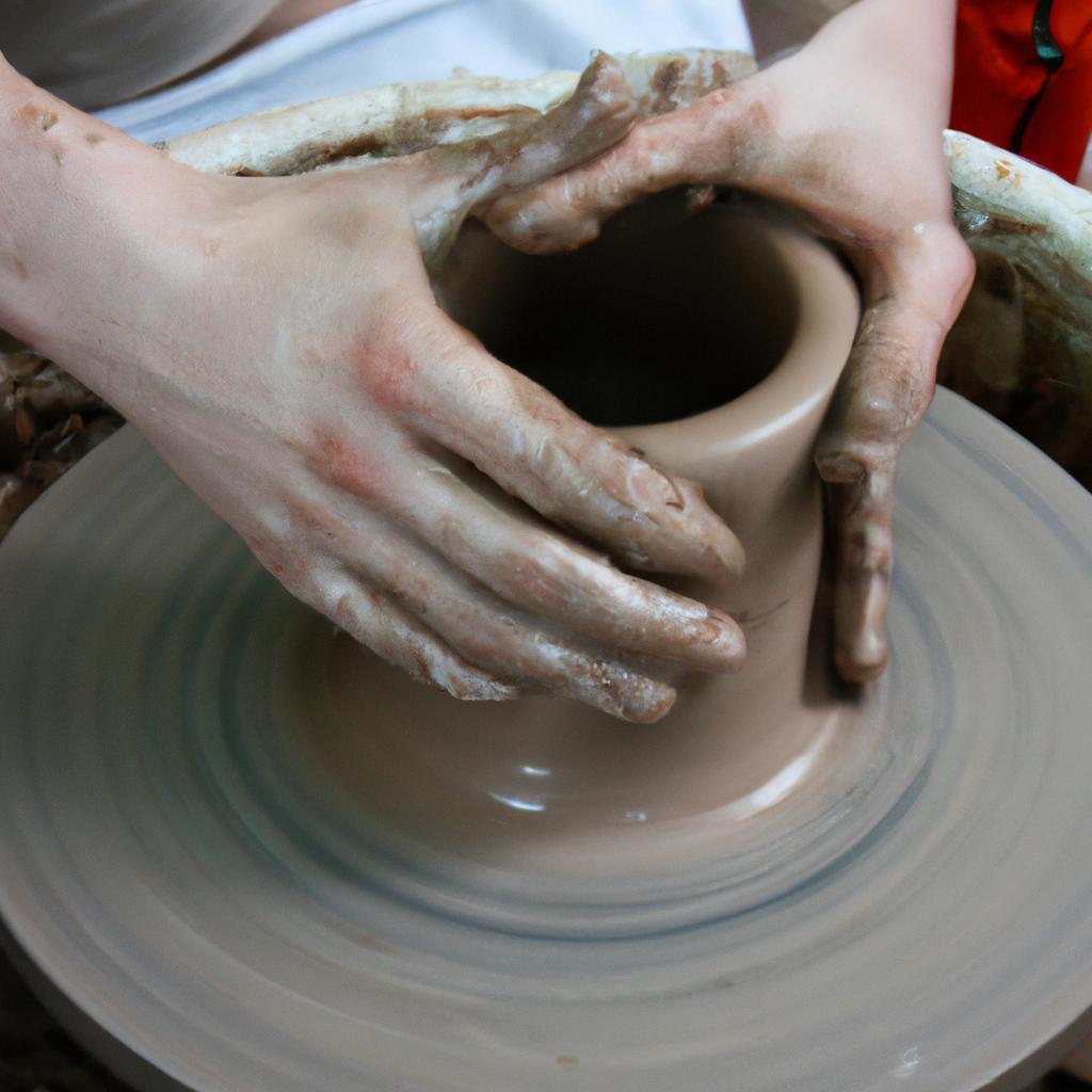 Person molding clay on pottery wheel